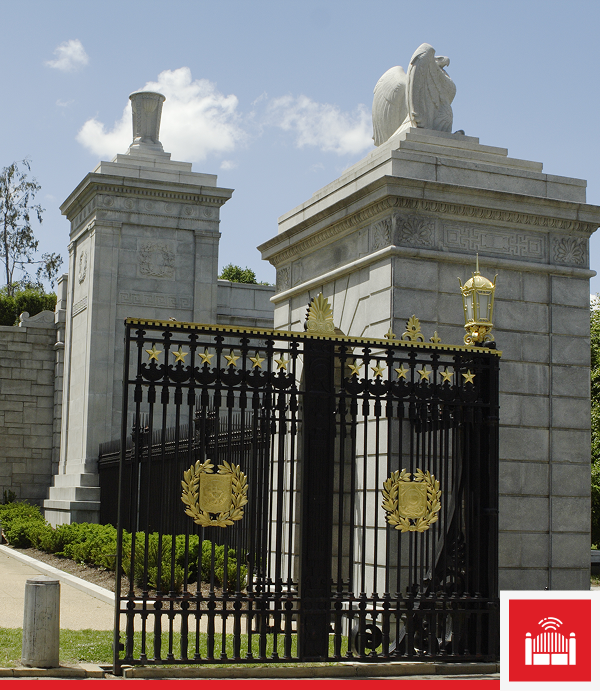 Ornate iron gate with stone columns and sculptures.